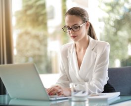 concentrated female entrepreneur typing on laptop in workplace