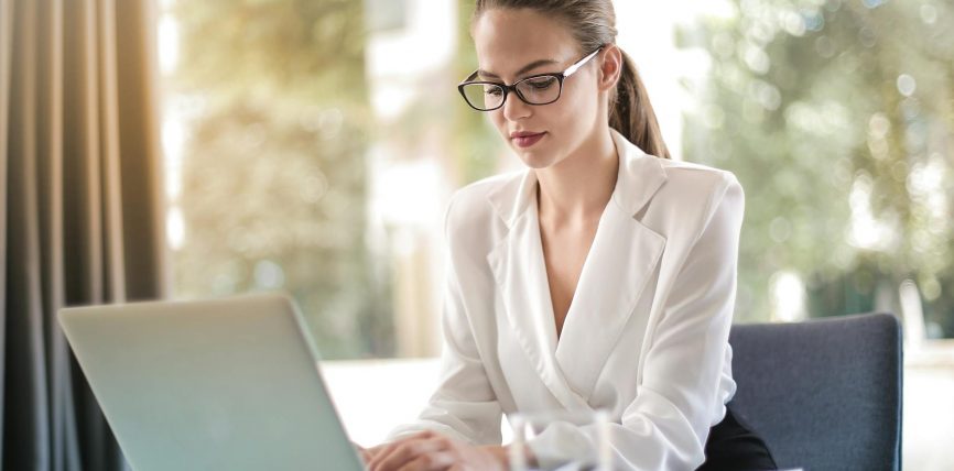 concentrated female entrepreneur typing on laptop in workplace