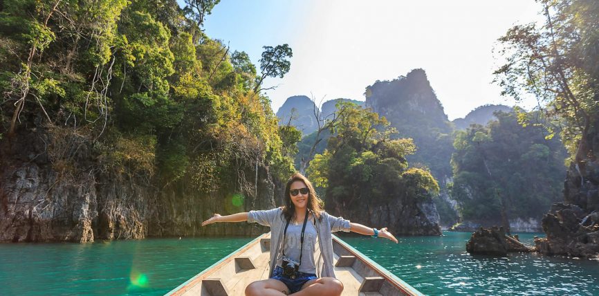 photo of woman sitting on boat spreading her arms