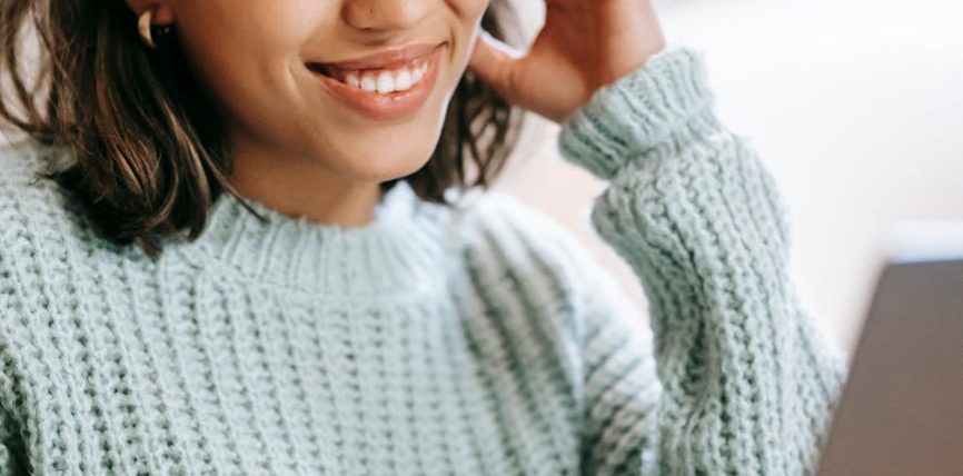 hispanic woman working remotely on laptop near notepad in apartment