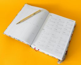 elegant open planner with golden pen on yellow background